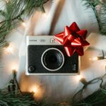 A christmas tree with a camera and a red bow