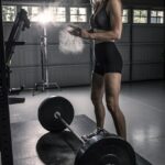 woman in black tank top and black shorts holding barbell