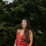 woman laughing while standing near tree