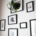 Person organizing framed photos on wall - improve productivity and time management