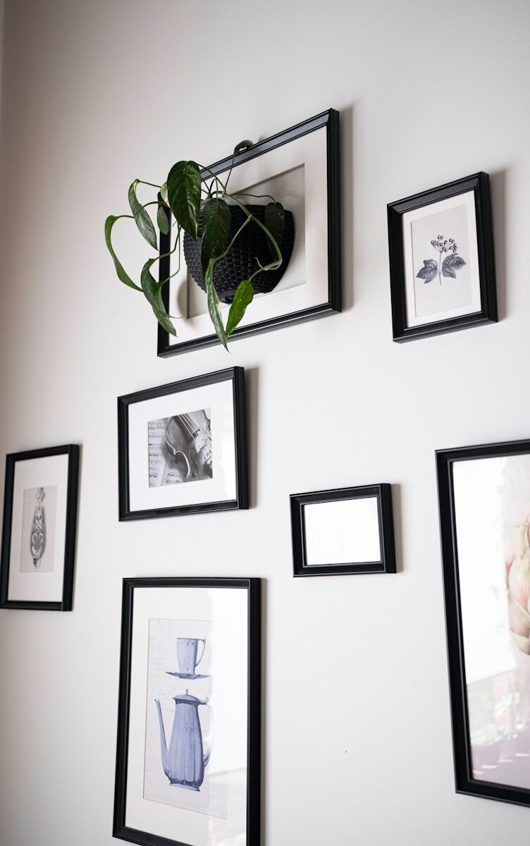 Person organizing framed photos on wall - improve productivity and time management